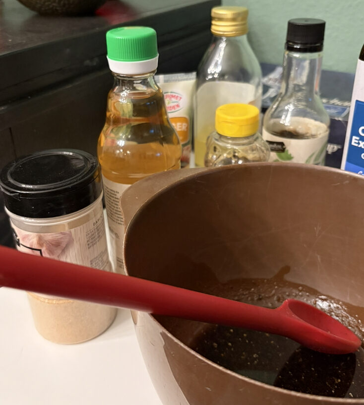Sauce ingredients and sauce in a brown bowl with a red spoon.